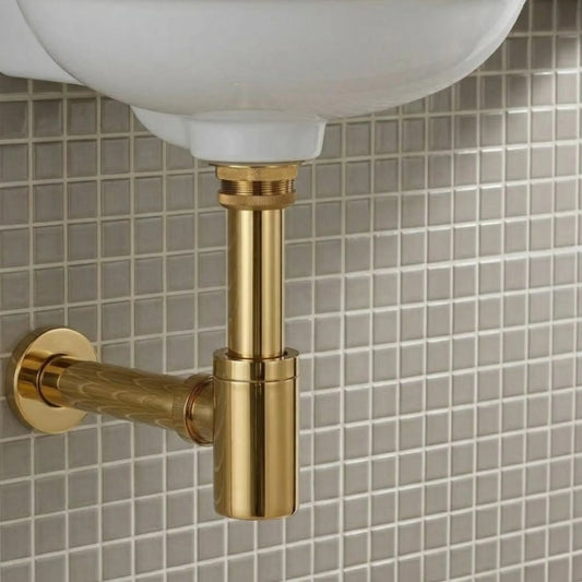 1-1/4 inch round bottle P-trap with box flange in unlacquered brass, installed under a white vessel sink on a gray mosaic tile wall