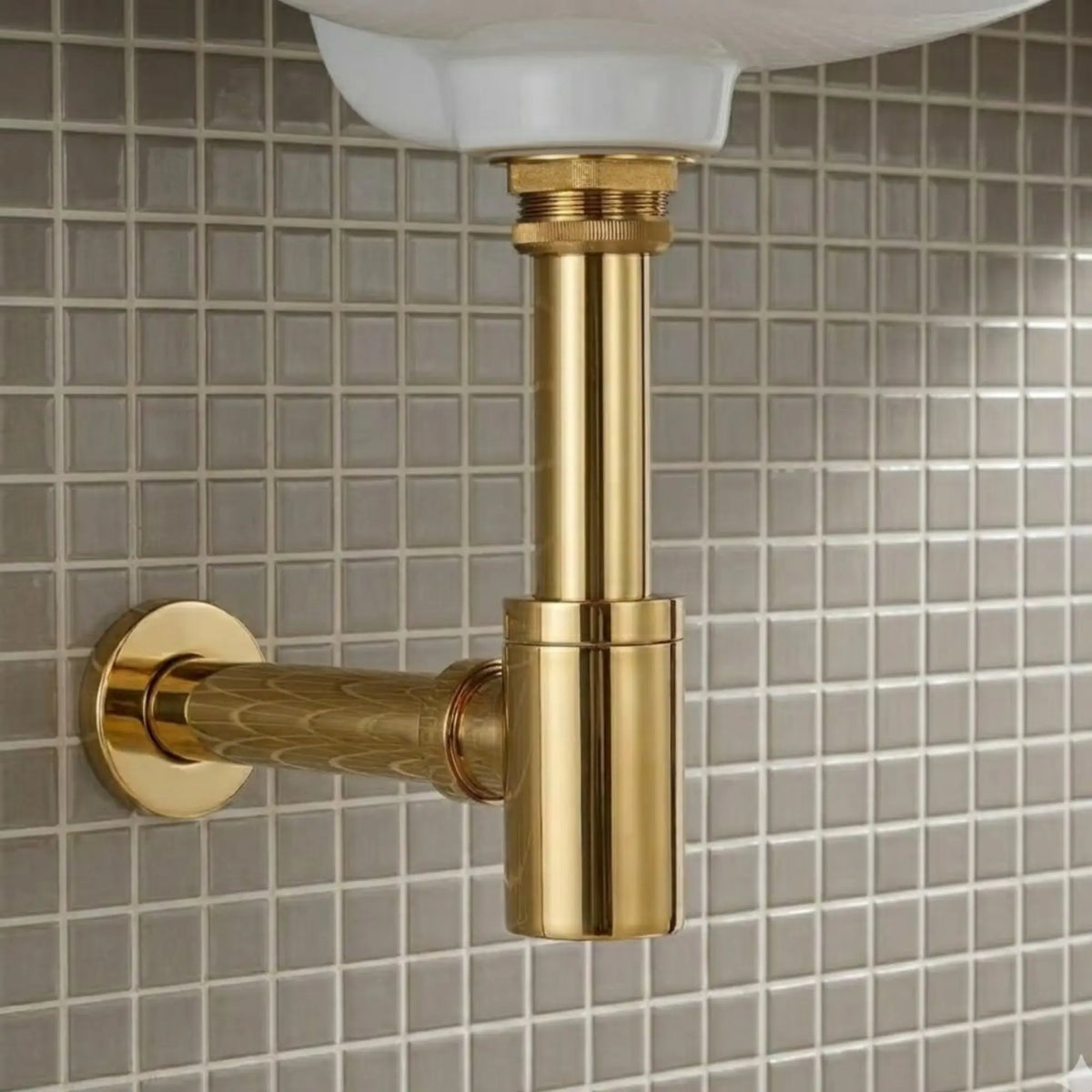 Close-up of 1-1/4 inch unlacquered brass bottle P-trap with round box flange and wall drain outlet installed under a white bathroom sink