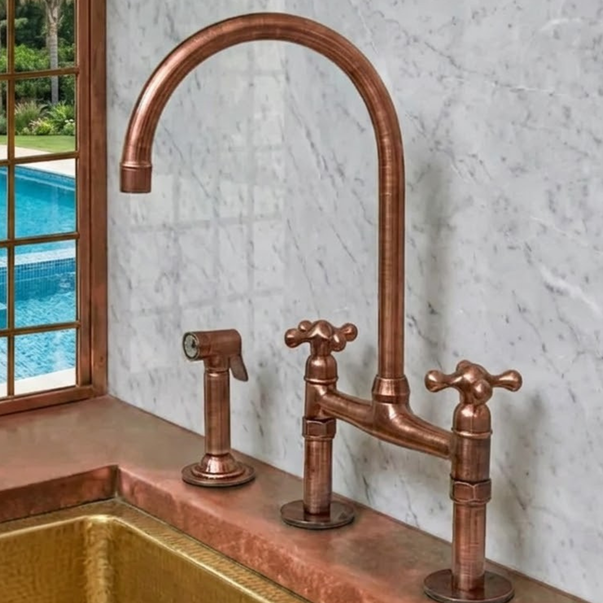 Copper faucet set on a marble countertop with a window view of a pool.