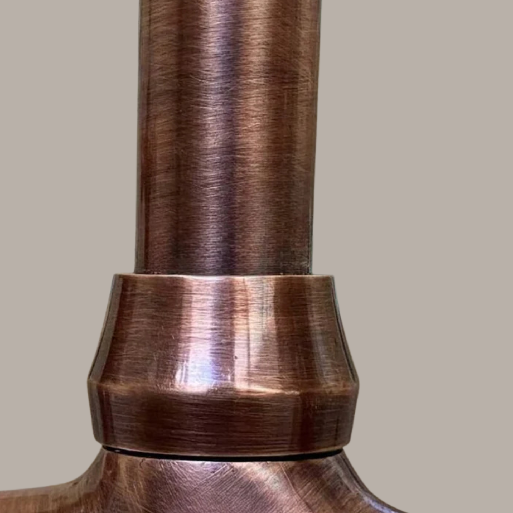 Close-up detail of handcrafted solid copper kitchen faucet body showing brushed vintage copper finish