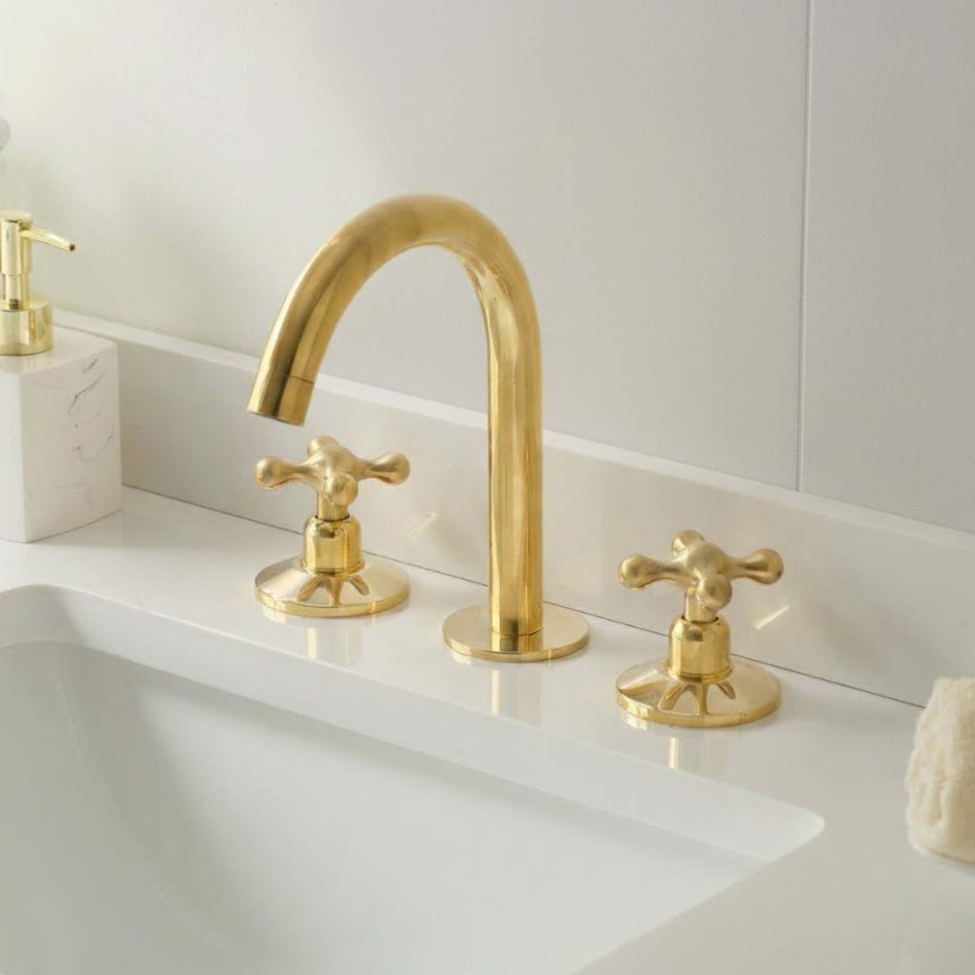 Luxury unlacquered brass deck mount bathroom faucet installed on modern white vanity sink