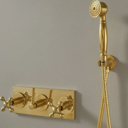 Gold bathroom faucet and handheld shower head on a gray wall