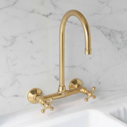 Ramsey wall-mounted kitchen faucet in unlacquered solid brass with cross handles installed on white marble backsplash