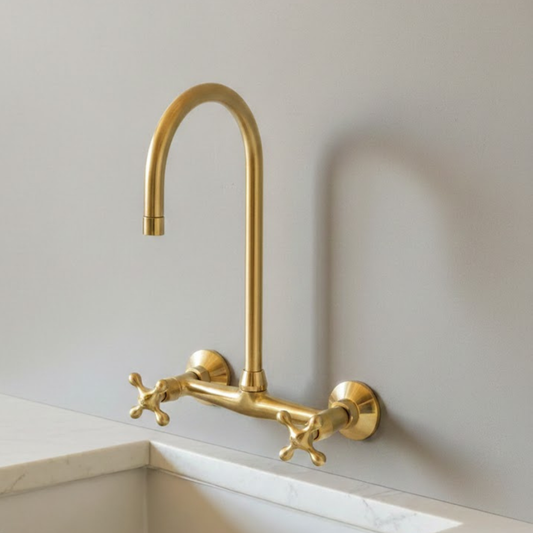 Unlacquered brass wall mounted kitchen faucet with cross handles and living patina finish