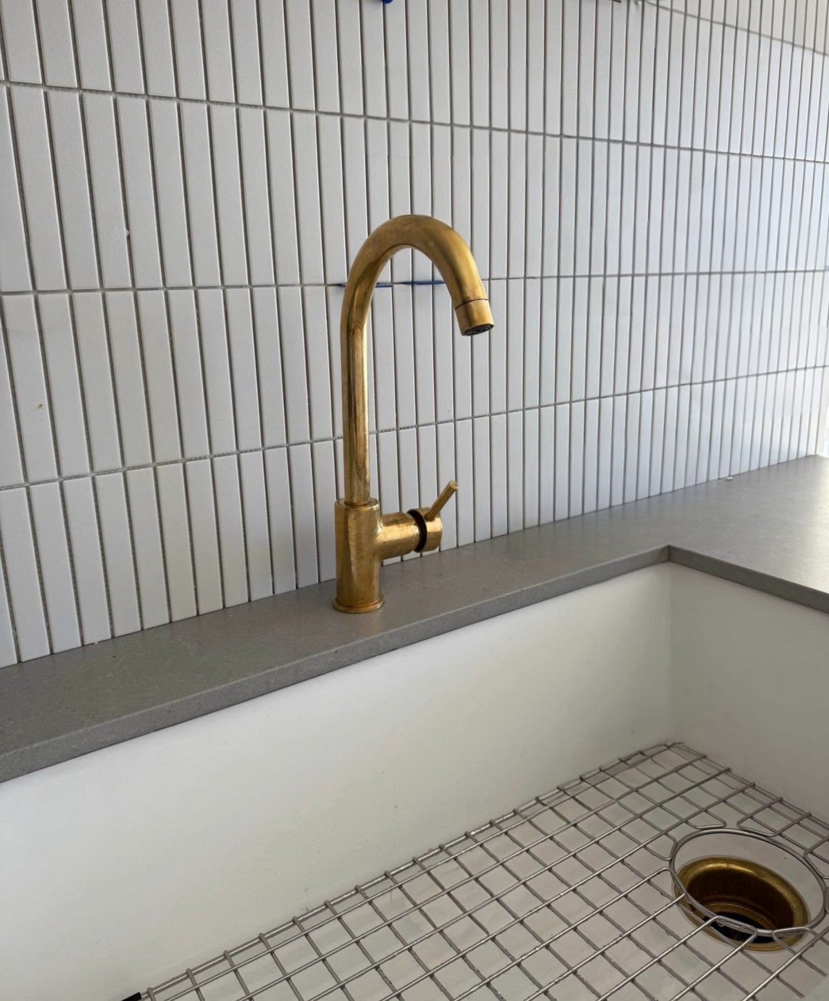 Gold faucet on a kitchen sink with tiled wall background