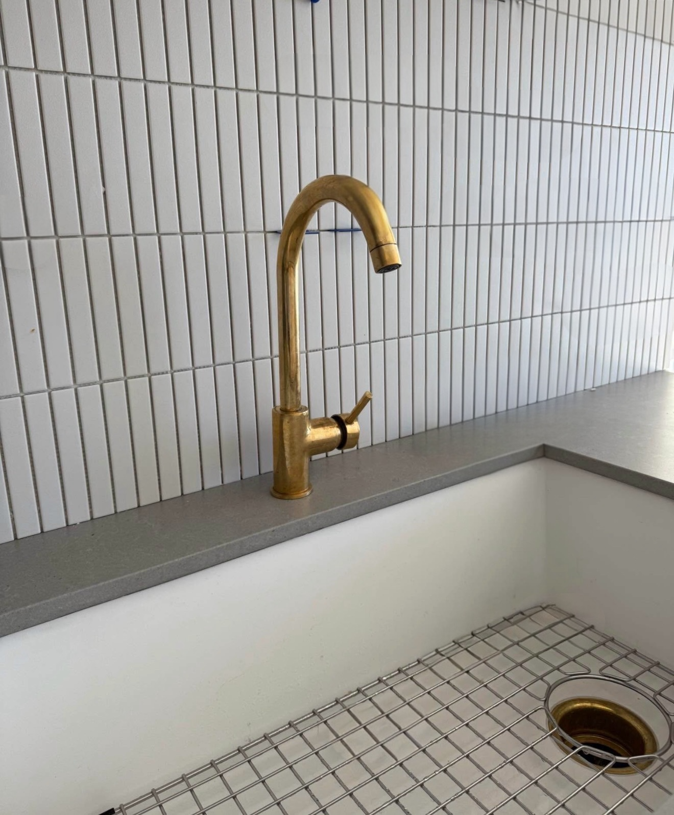 Gold faucet on a kitchen sink with tiled wall background