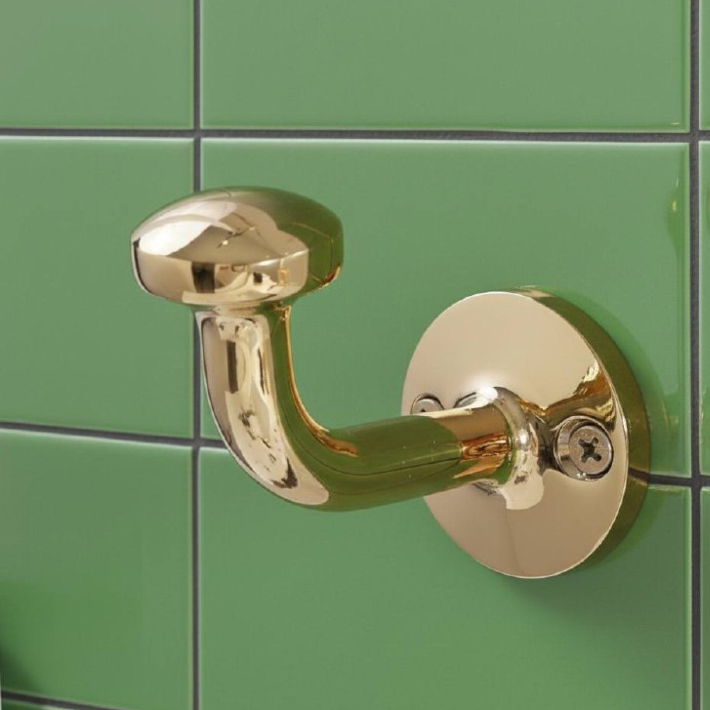 Side view of a solid unlacquered brass wall hook highlighting the curved hook shape and polished natural brass surface.
