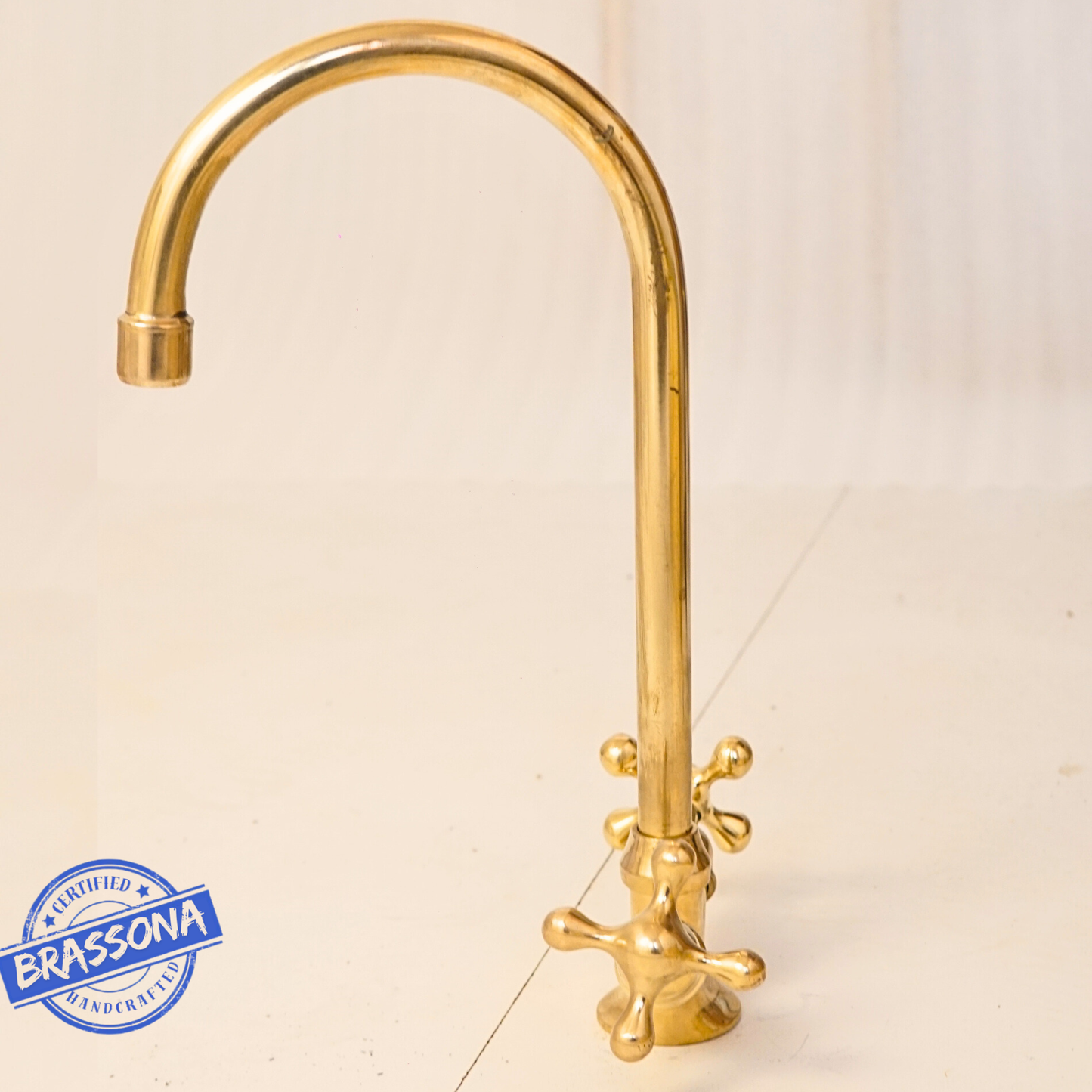 Side profile of an unlacquered brass gooseneck faucet highlighting the smooth curved spout and polished natural brass surface.