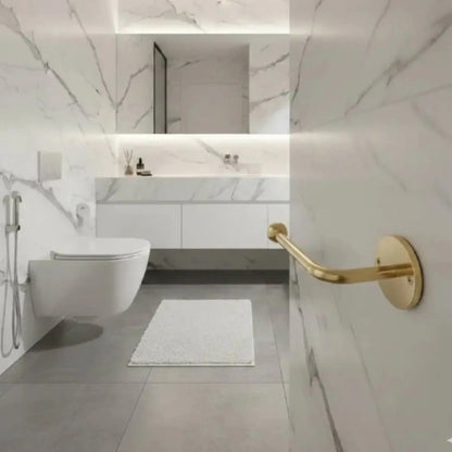 Wall-mounted unlacquered brass toilet paper holder in modern marble bathroom, solid brass bathroom accessory with natural patina finish