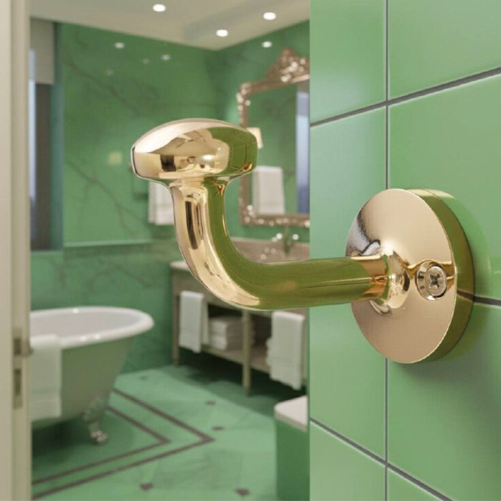 Unlacquered solid brass wall hook installed in a bathroom interior, blending classic design with modern green ceramic tiles.