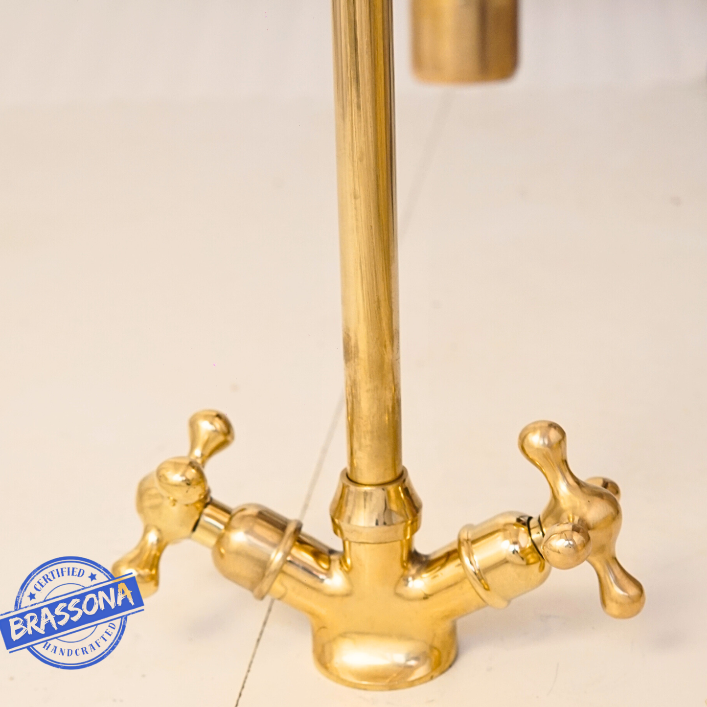 Front view of a vintage-style unlacquered brass bathroom sink faucet with dual cross handles and elegant gooseneck spout.