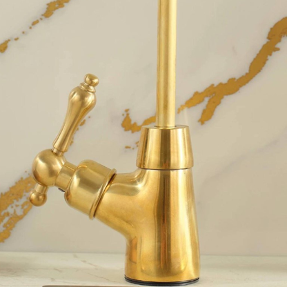 Detail view of the vintage-style cross handle and ornate base of a brass faucet.