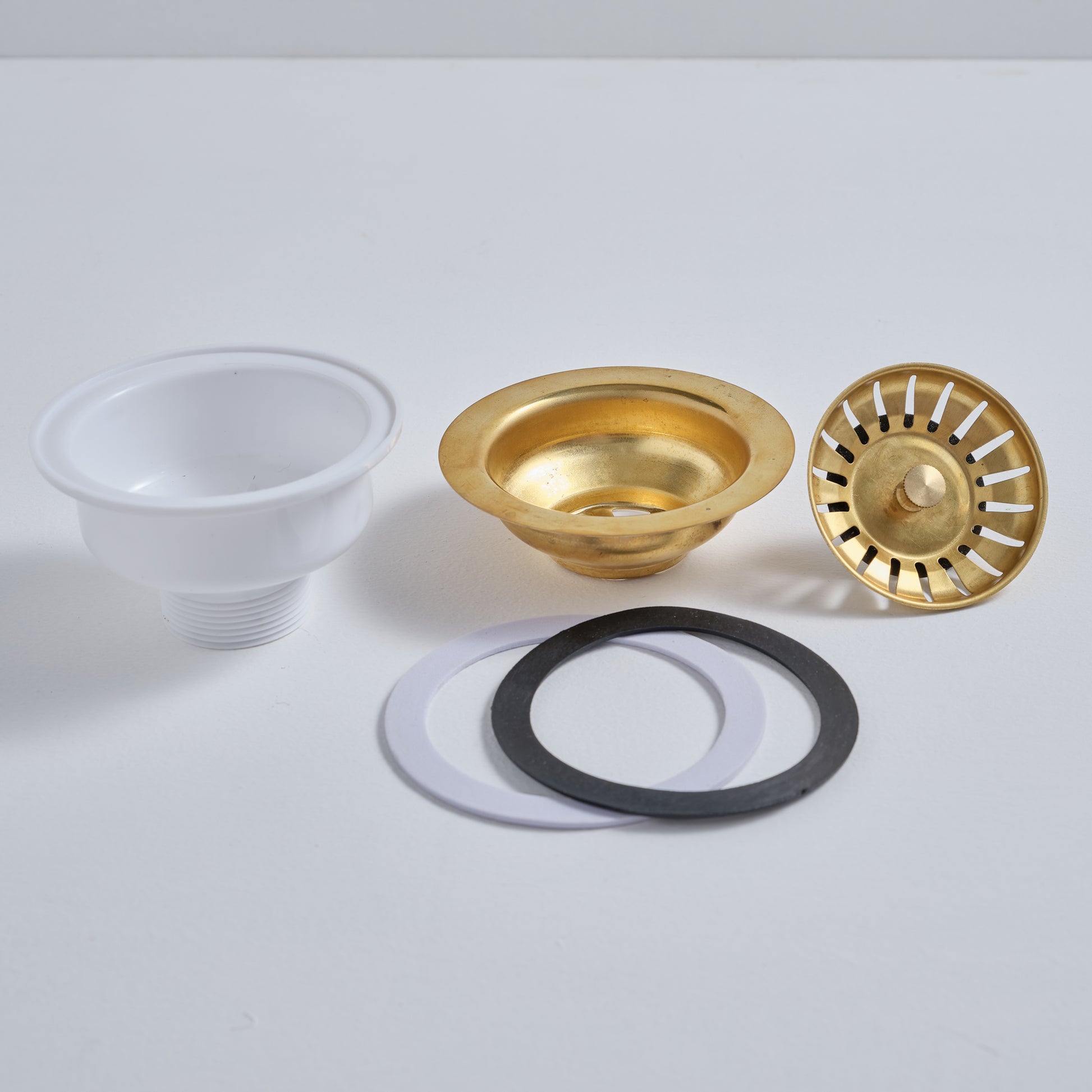 Exploded view of the brass sink drain showing the solid brass top, rubber gasket, and durable PVC base.
