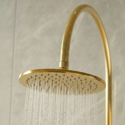 Close-up of the luxury unlacquered brass rainfall shower head with water flowing, showcasing the spray pattern.