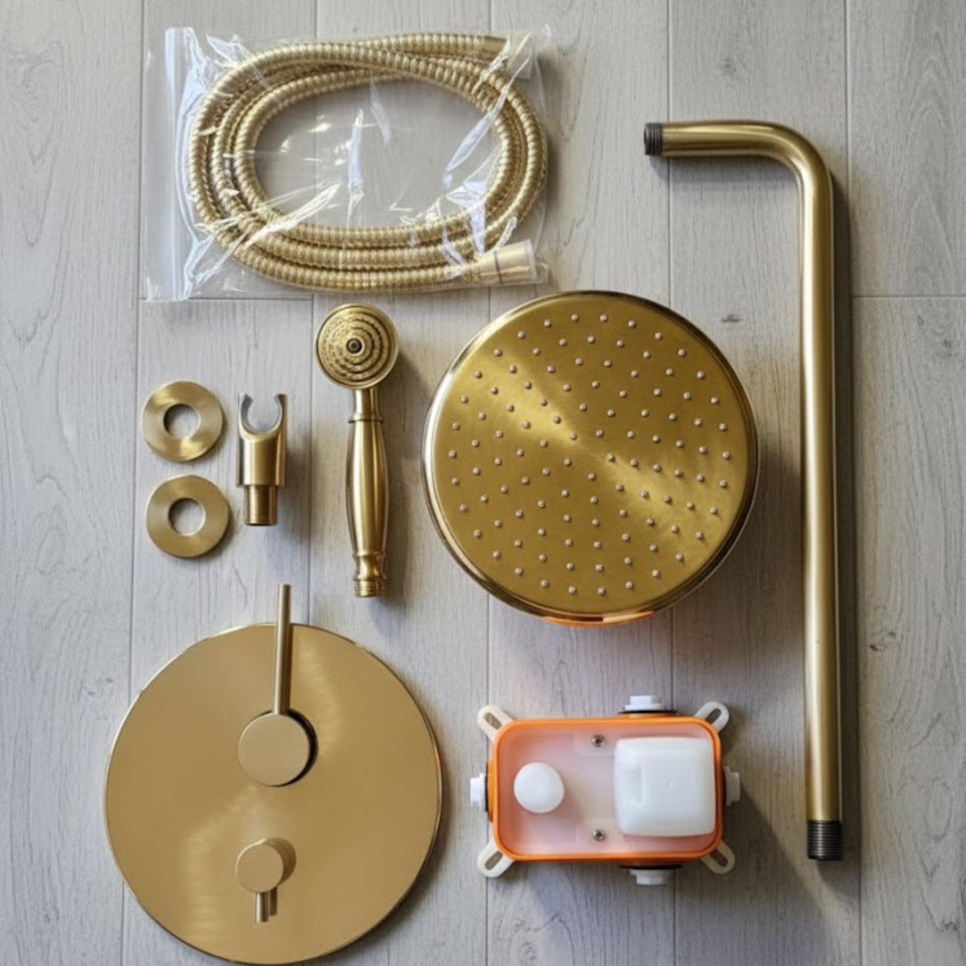 Flat lay of all included components: rainfall head, arm, handheld wand, hose, valve cover, and rough-in valve.