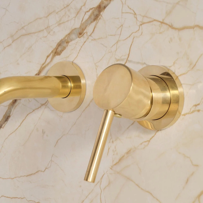 Single-handle control detail on unlacquered brass wall-mounted bathroom faucet