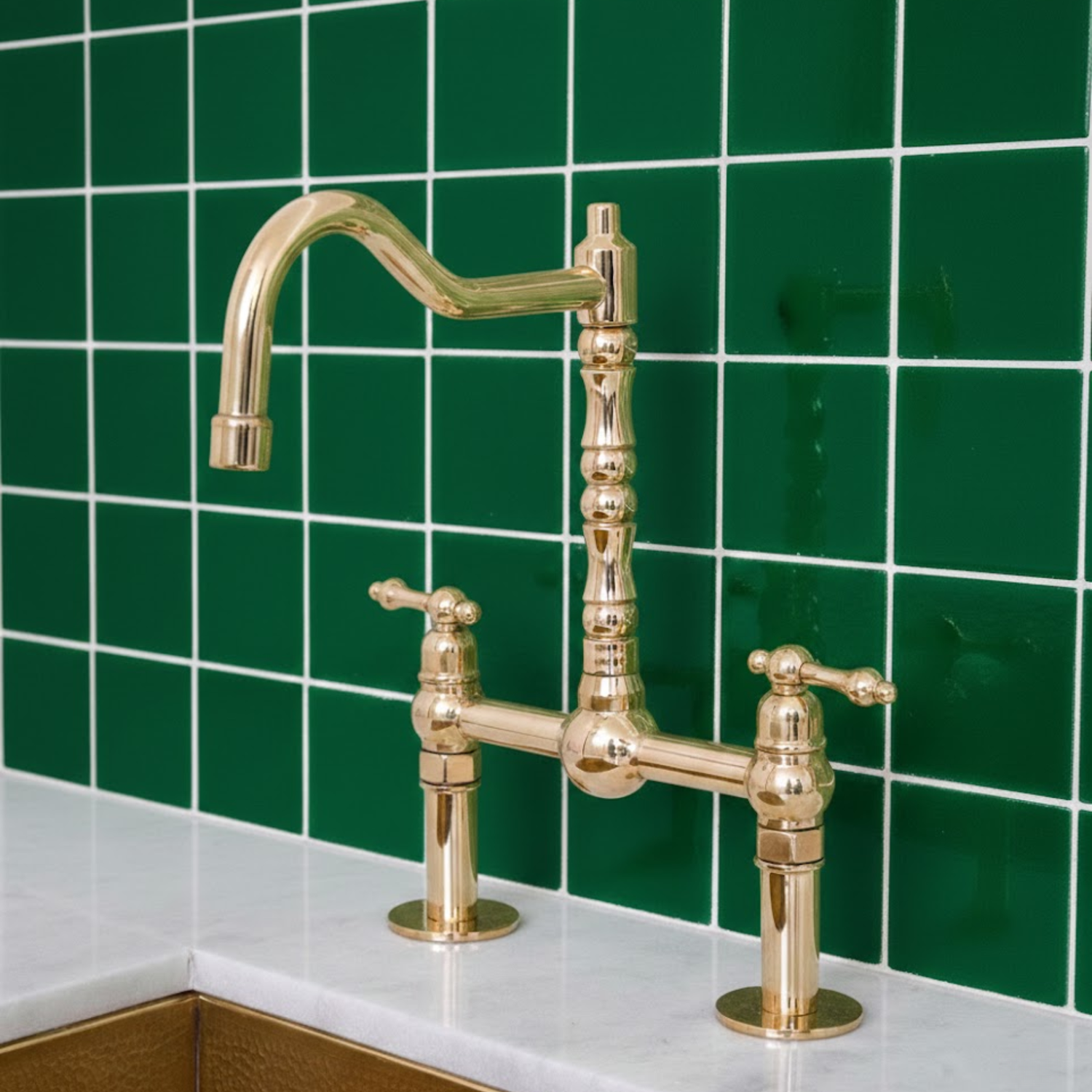 Solid brass bridge kitchen faucet installed against green tiled wall in luxury kitchen setting.
