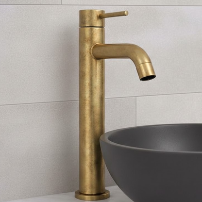 Castello unlacquered solid brass vessel sink faucet with single lever installed beside gray round basin in modern bathroom