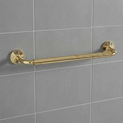 Unlacquered brass wall-mounted grab bar installed on grey subway tiles, featuring traditional round decorative flanges and exposed screws.