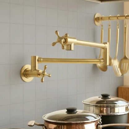 Gold kitchen faucet mounted on a tiled wall with pots below.
