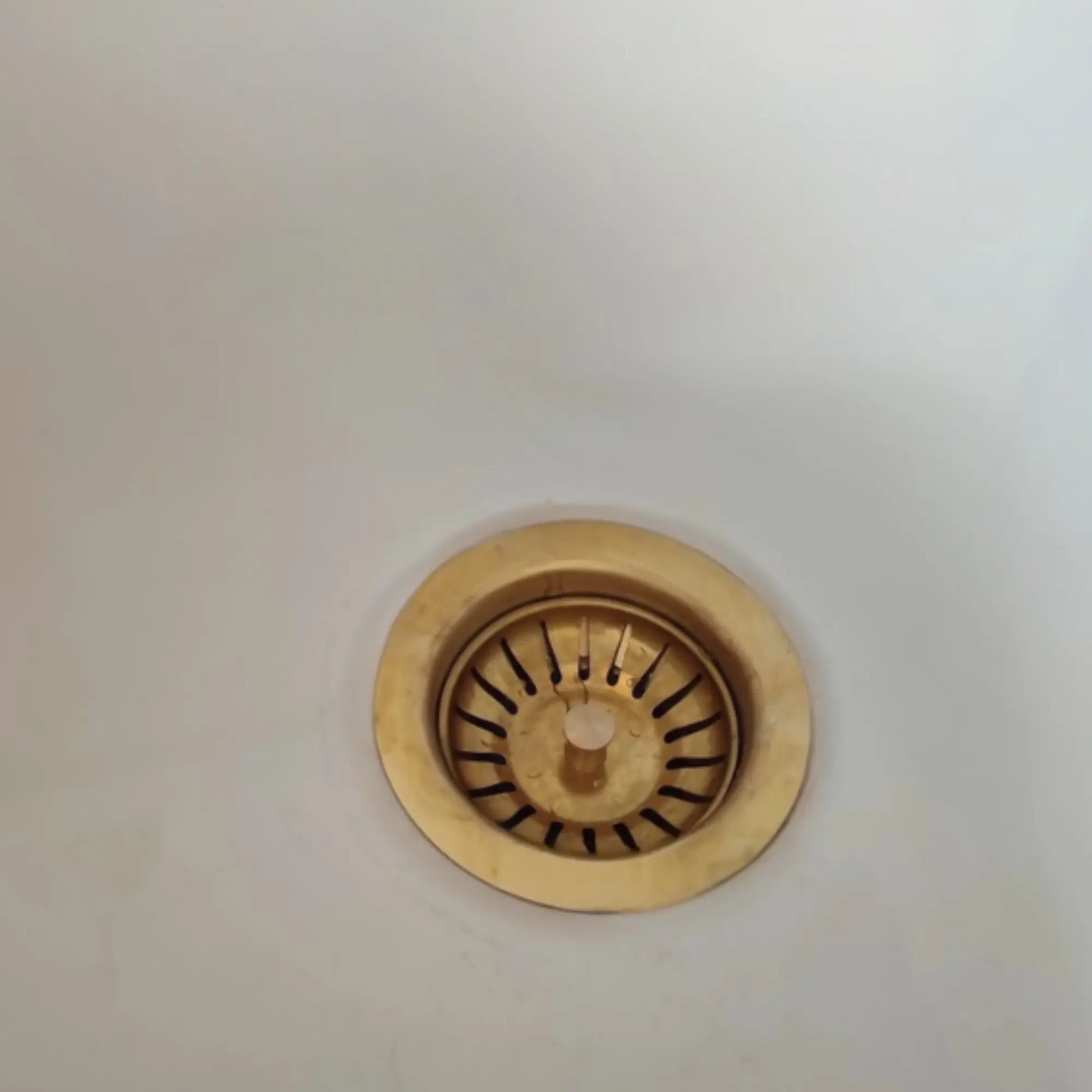 Gold sink drain cover on a white background