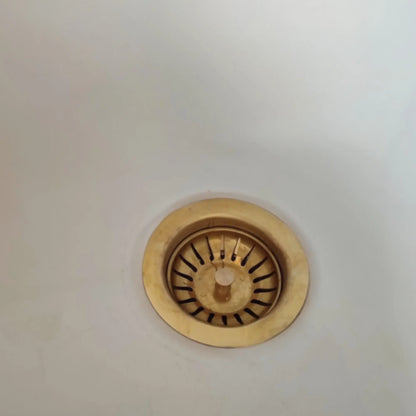 Gold sink drain cover on a white background