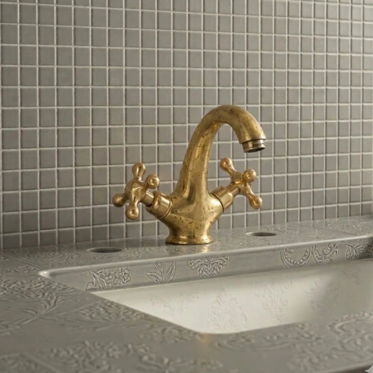 Unlacquered brass bathroom sink faucet with cross handles showing natural living patina on decorative vanity sink