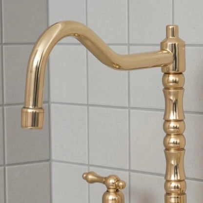 Unlacquered brass bridge kitchen faucet with high arc spout and vintage design installed on countertop with tiled backsplash