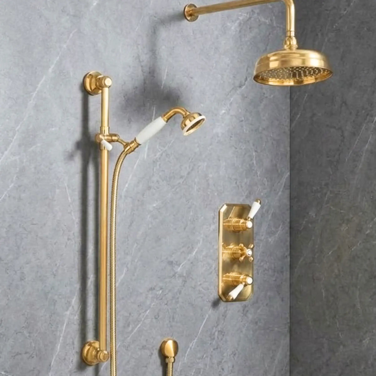 Unlacquered brass concealed thermostatic shower system with overhead rainfall head, adjustable slide rail, and porcelain-handle handshower mounted on grey marble wall