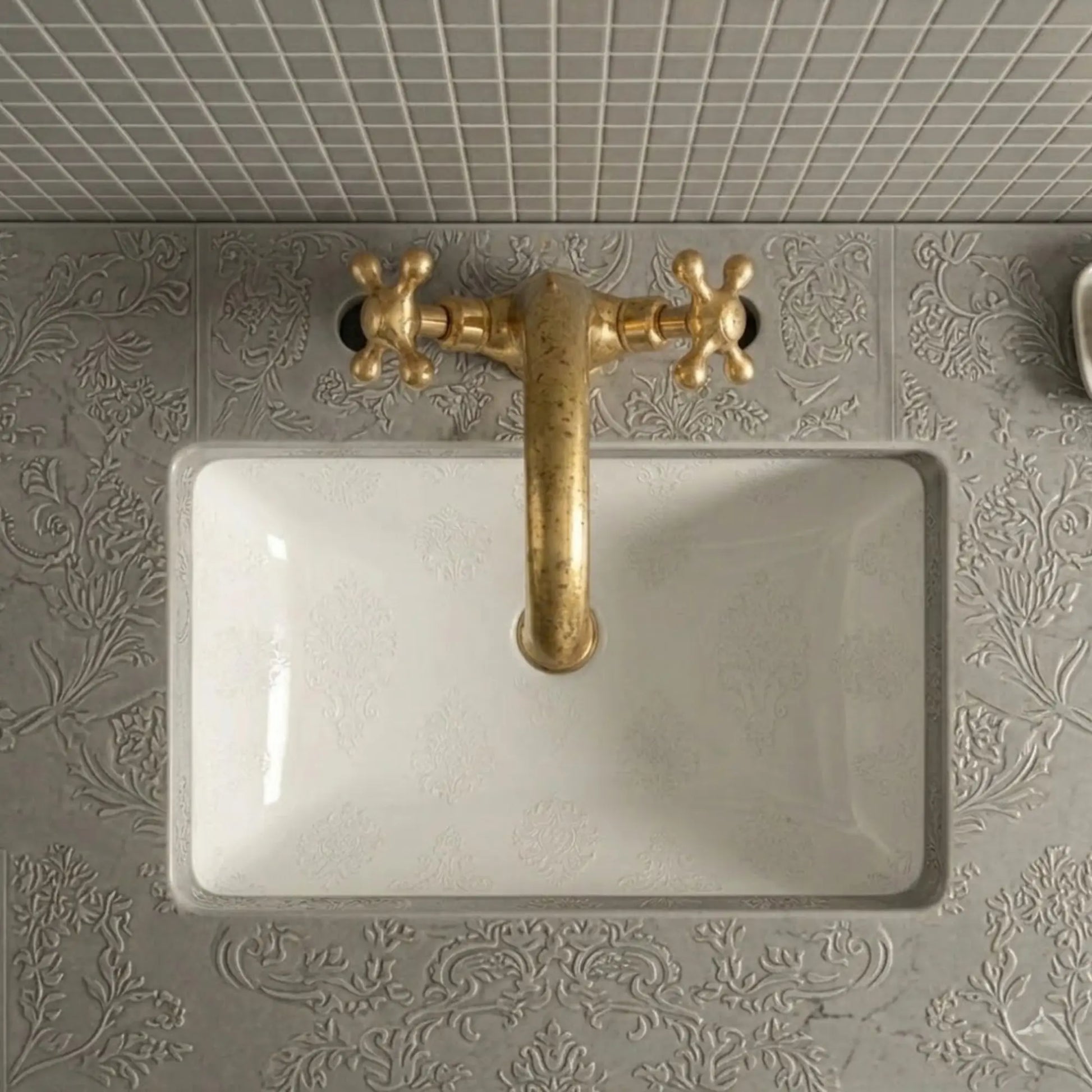 Unlacquered brass bathroom sink faucet with cross handles top view installed on decorative vanity sink
