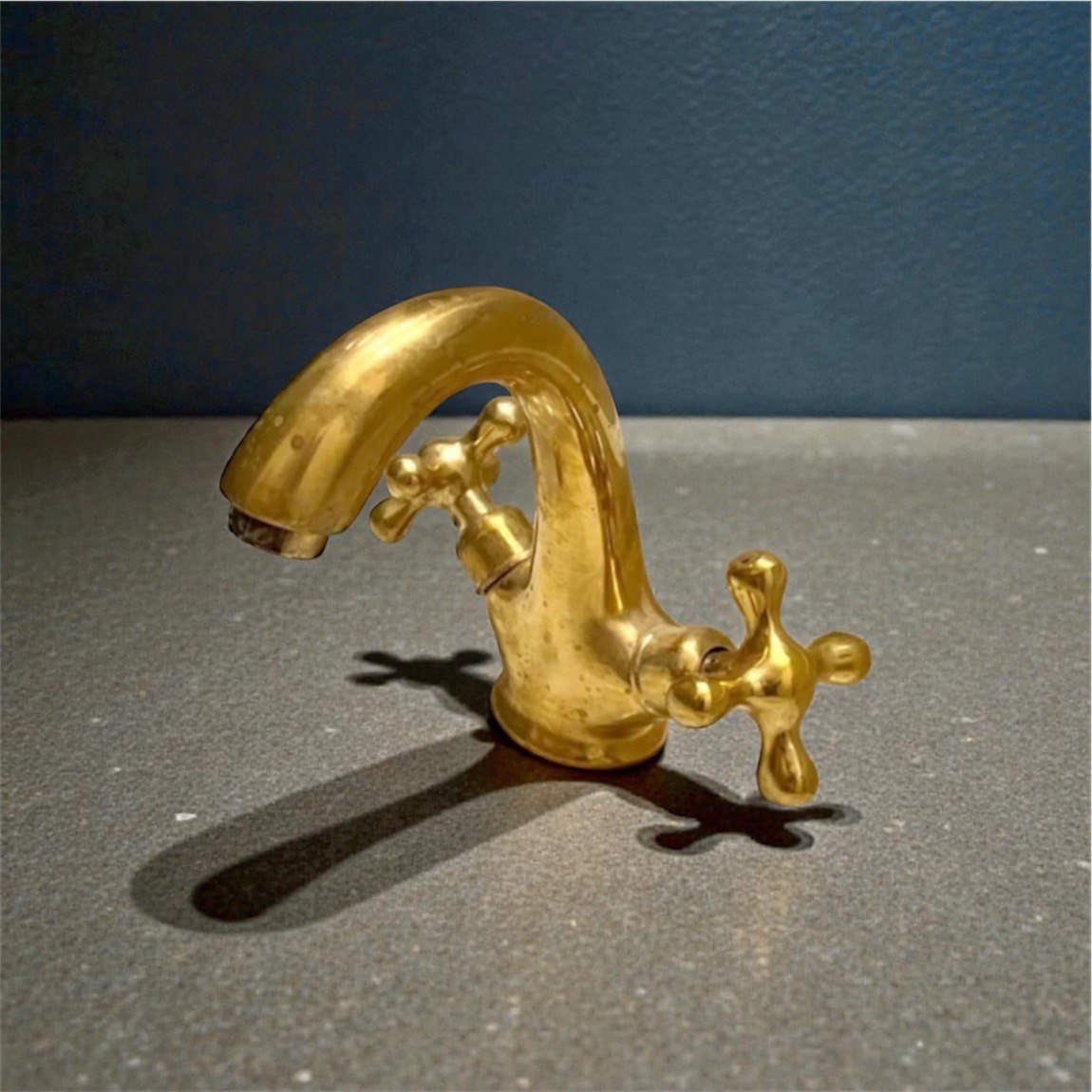 Unlacquered brass bathroom faucet featuring traditional double cross handles and living finish