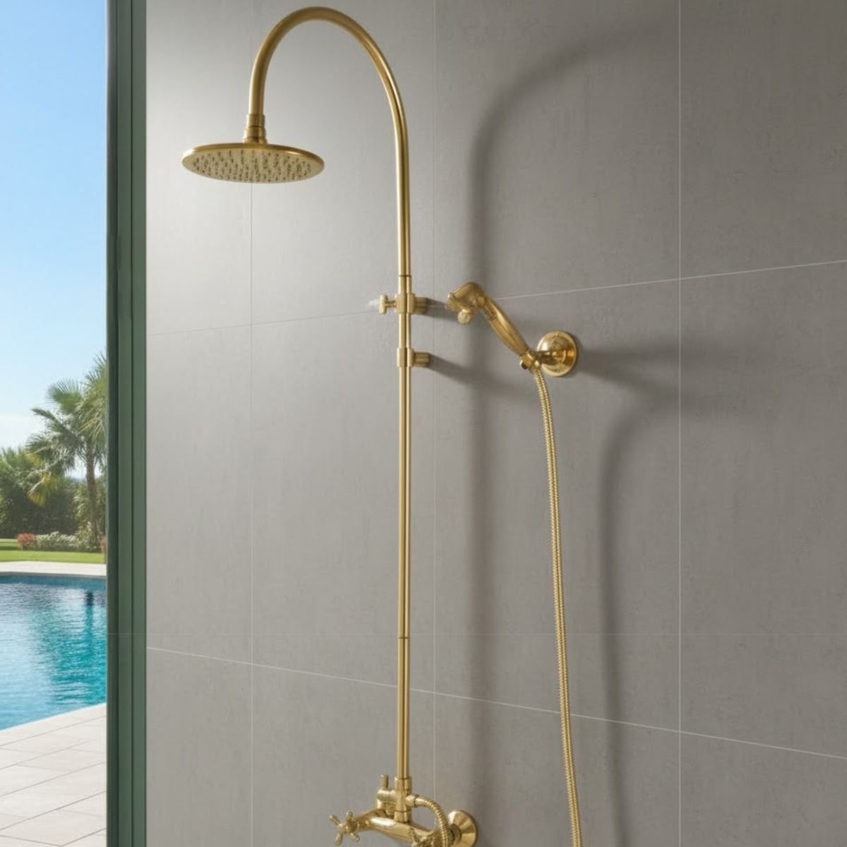 Brass shower system mounted on a gray tiled wall with a pool and garden view outside.
