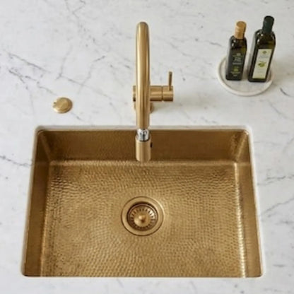 Unlacquered brass faucet with pop-up drain in hammered brass sink, top-down view