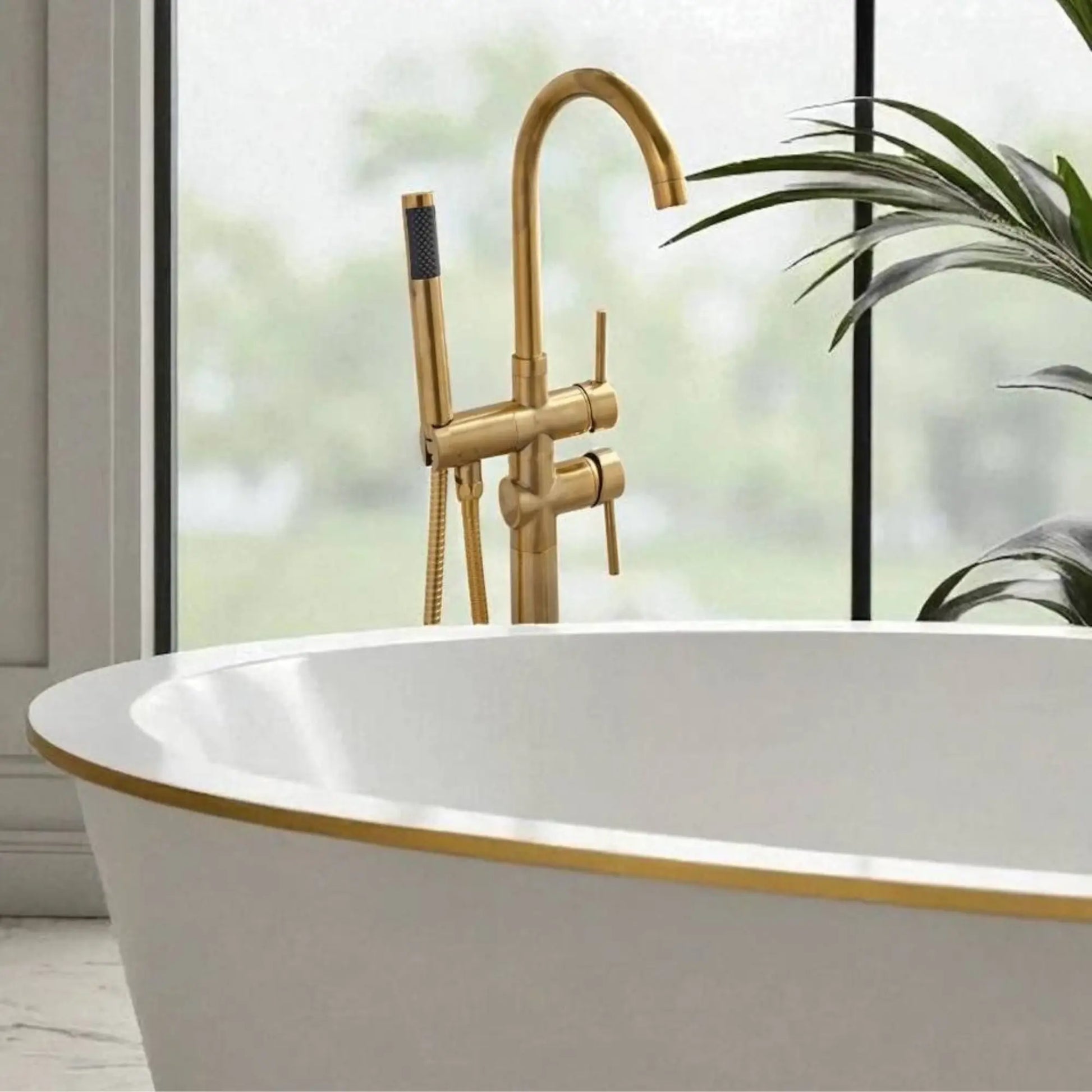 Close-up of the unlacquered brass floor-mount bathtub faucet showing the dual-handle controls and high-flow handheld shower.
