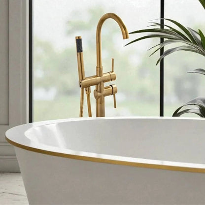 Close-up of the unlacquered brass floor-mount bathtub faucet showing the dual-handle controls and high-flow handheld shower.