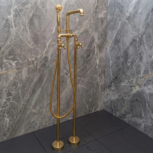 Unlacquered brass freestanding bathtub faucet with handheld shower, solid brass floor mounted tub filler beside gray marble wall