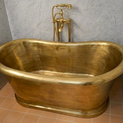 Unlacquered brass freestanding tub faucet installed with clawfoot bathtub in luxury bathroom setting