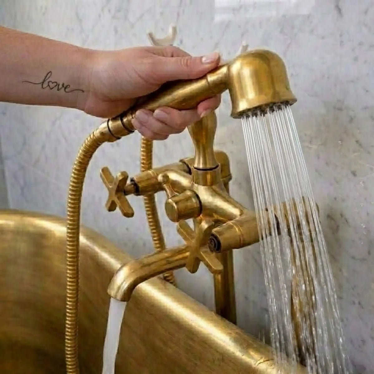 Unlacquered brass freestanding tub faucet with telephone hand shower showing strong water flow in clawfoot bathtub