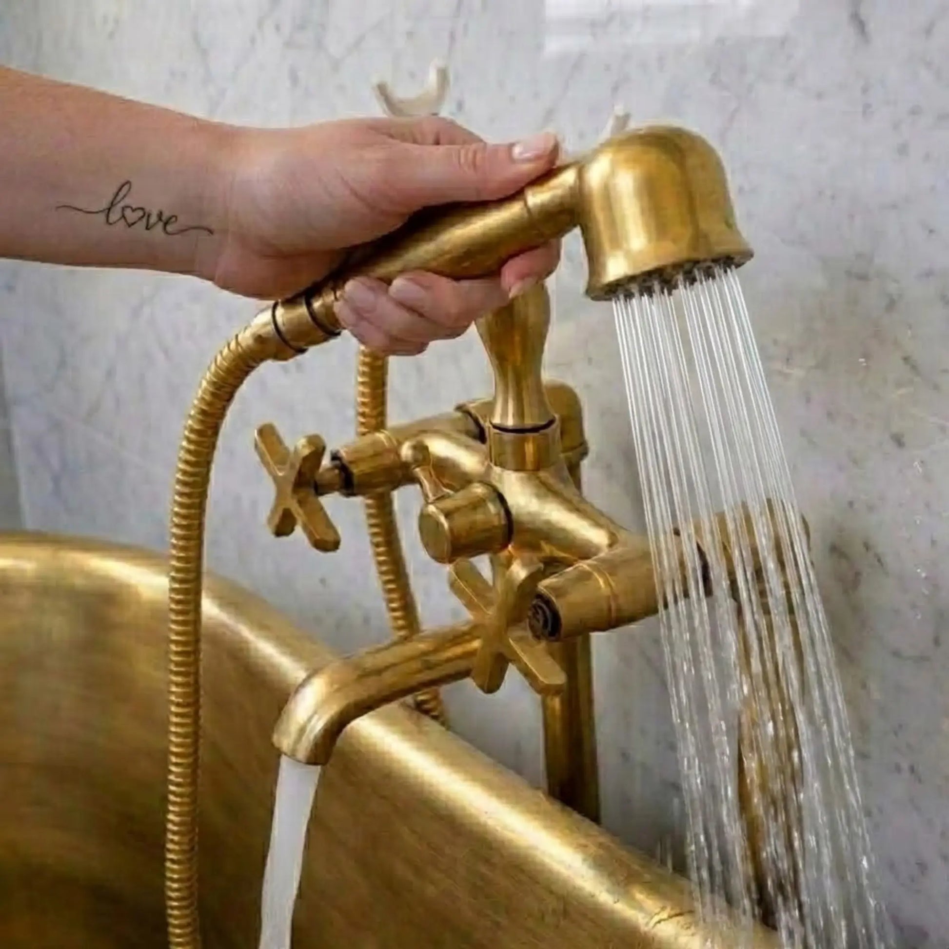 Unlacquered brass freestanding tub faucet with telephone hand shower showing strong water flow in clawfoot bathtub