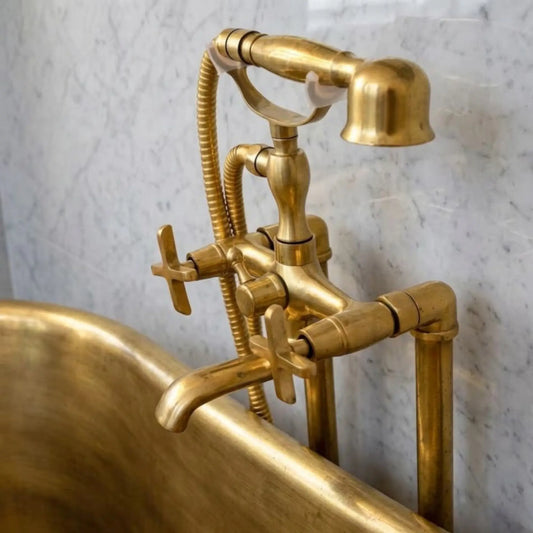 Unlacquered brass freestanding tub faucet with telephone hand shower installed on clawfoot bathtub