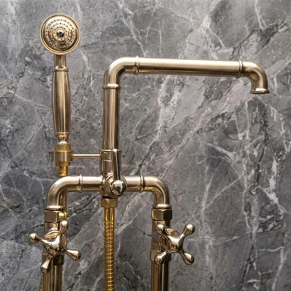 Unlacquered brass freestanding bathtub faucet with handheld shower and cross handles on gray marble wall
