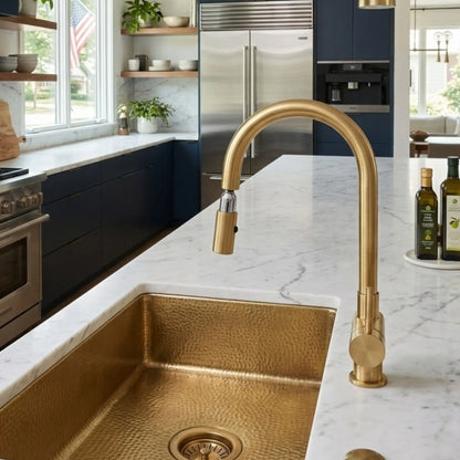 Unlacquered brass high arc pull down faucet with hammered brass sink in navy kitchen