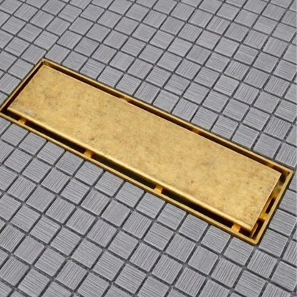 Unlacquered brass linear shower drain installed flush on gray mosaic tile shower floor – BrassOna