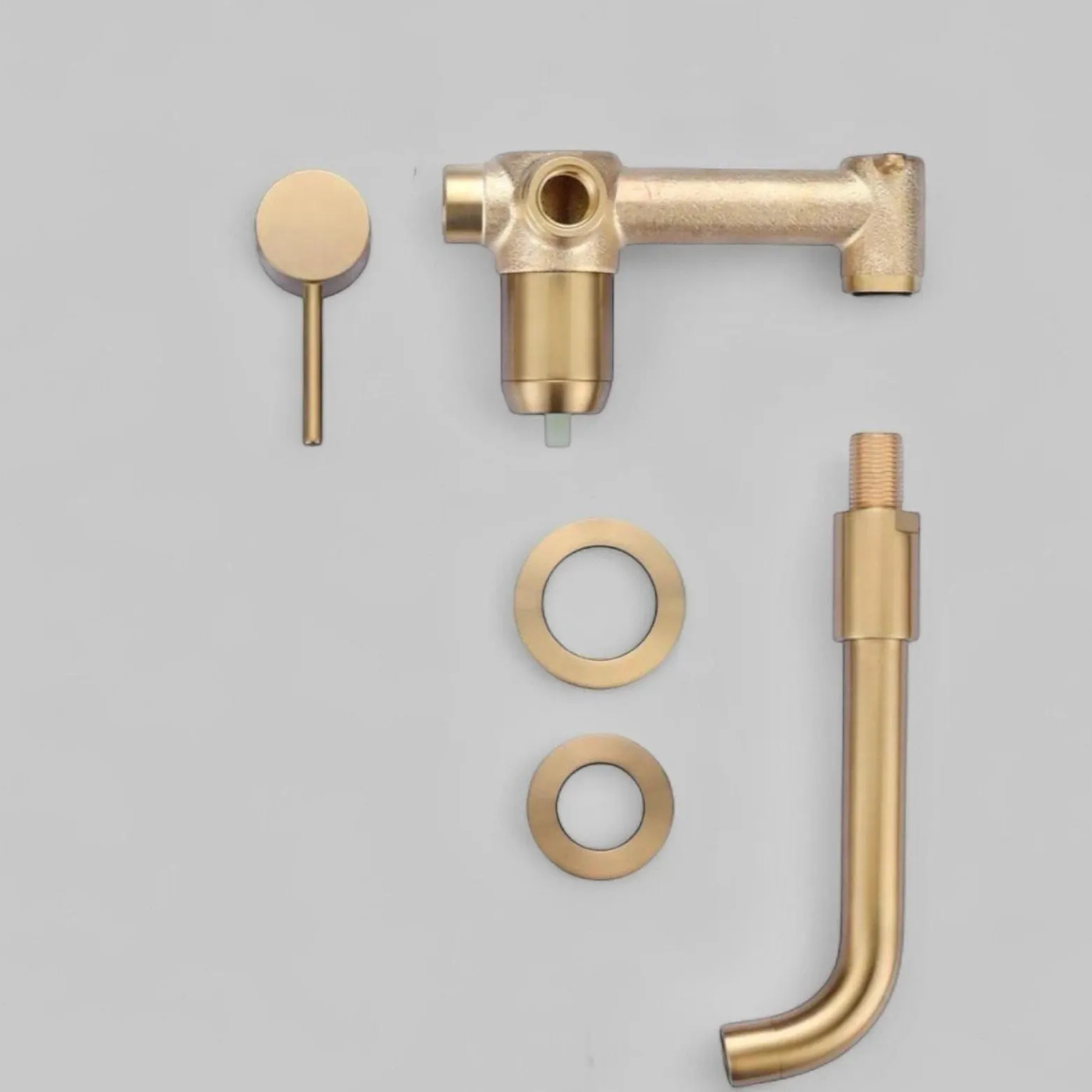 Unlacquered brass wall-mount bathroom faucet component set including spout, handle, escutcheons, and mounting parts