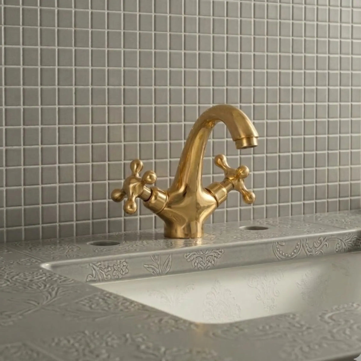 Unlacquered solid brass bathroom sink faucet with cross handles installed on decorative vanity sink with tiled backsplash