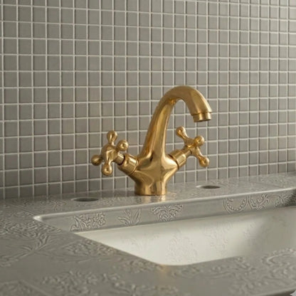 Unlacquered solid brass bathroom sink faucet with cross handles installed on decorative vanity sink with tiled backsplash