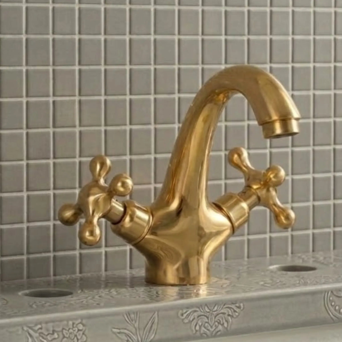 Unlacquered solid brass bathroom sink faucet with cross handles installed on decorative vanity sink