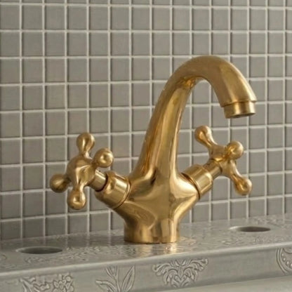 Unlacquered solid brass bathroom sink faucet with cross handles installed on decorative vanity sink