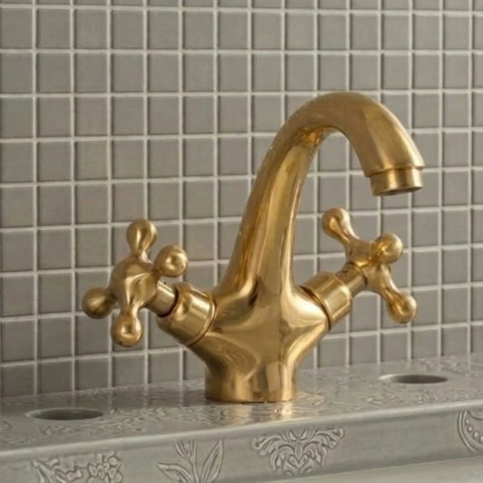 Unlacquered solid brass bathroom sink faucet with cross handles installed on decorative vanity sink