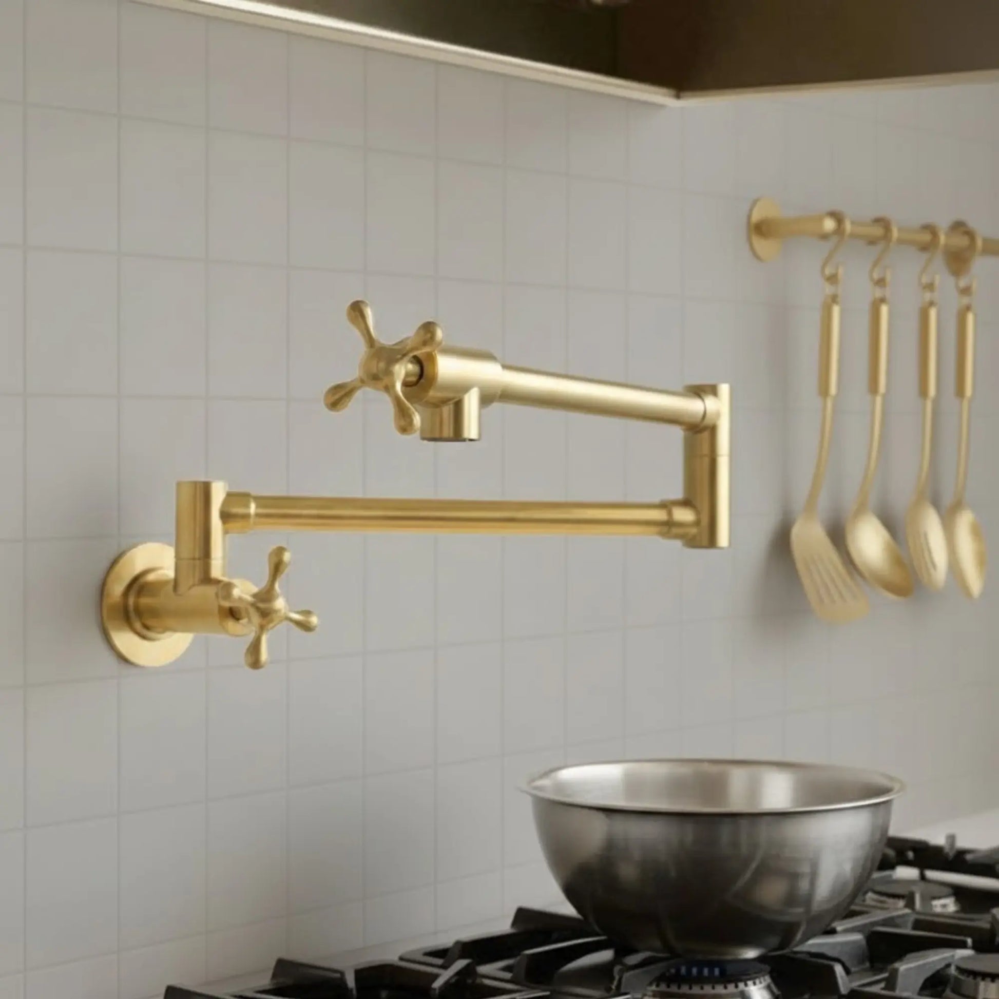 Gold kitchen faucet and utensils on a tiled wall